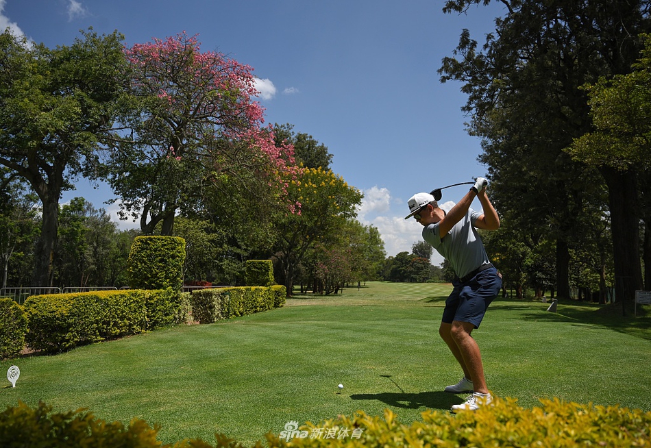 李昊桐在练习果岭上仔细研判推杆线路，背景中的会所建筑颇具殖民时期风格。