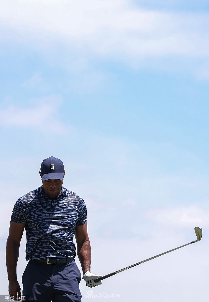 伍兹在烈日下擦拭额头，坚毅的侧脸写满了与伤痛和逆境对抗的专注。