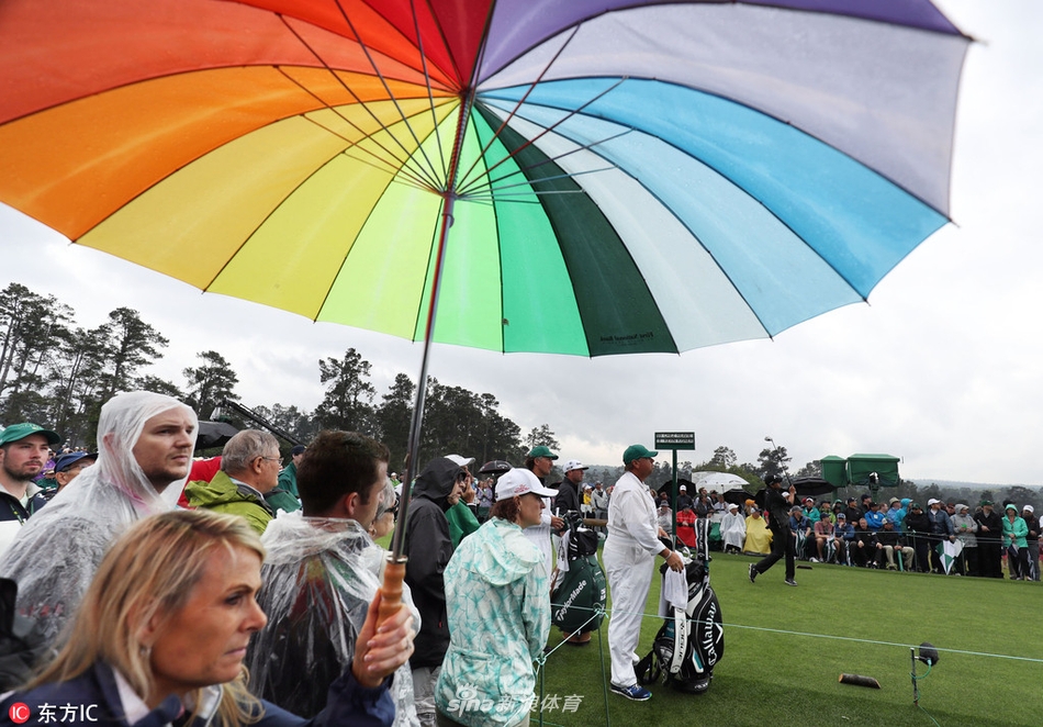 雨势稍歇，几把收拢的彩色雨伞斜靠在白色的栏杆上，水珠顺着伞尖滴落，在木质地面上留下深色的印记，仿佛一场华丽演出的余韵。