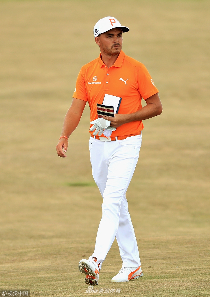 里奇·福勒身着标志性橙色球衣在果岭边观察推击线路，神情专注。