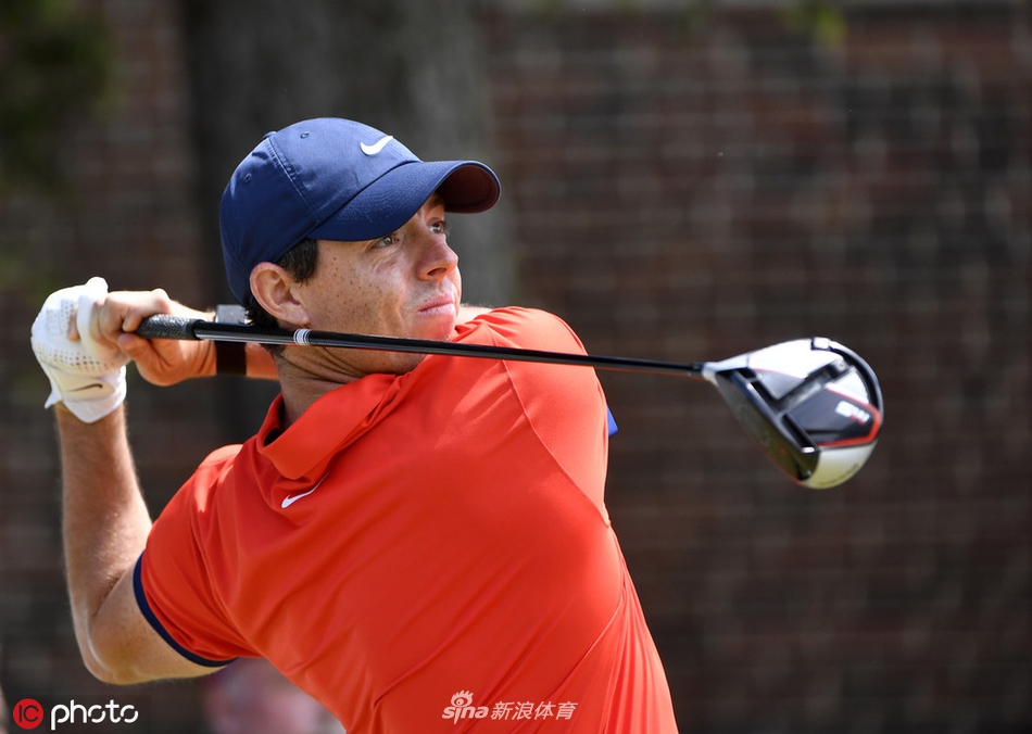 麦克罗伊在果岭上俯身准备推杆，神情凝重，这一推的结果可能关乎冠军的归属，气氛紧张