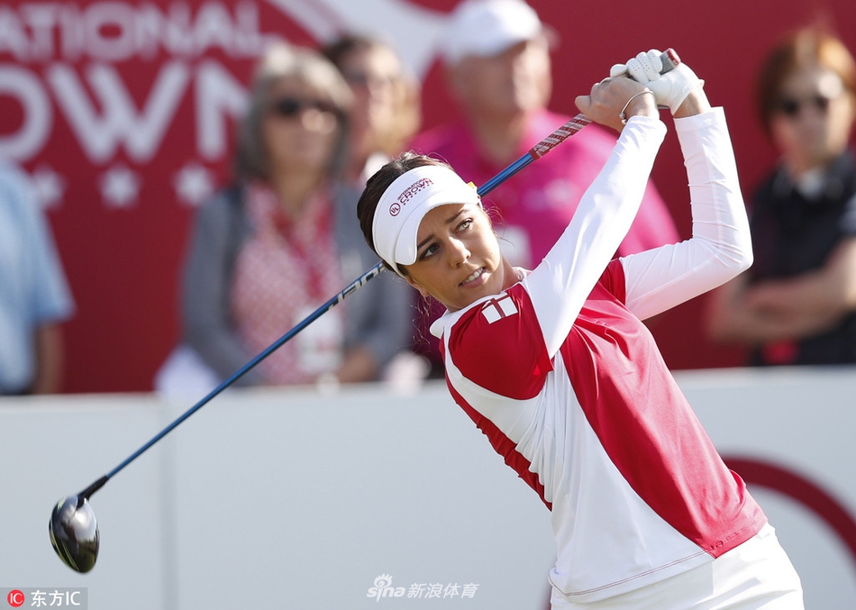 一位女子高尔夫球手在球道上专注地观察推杆路线,阳光洒在翠绿的果岭上,气氛宁静而紧张。