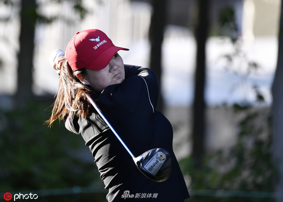 尹天琪在果岭边仔细阅读推杆线路，微风轻拂她的帽檐