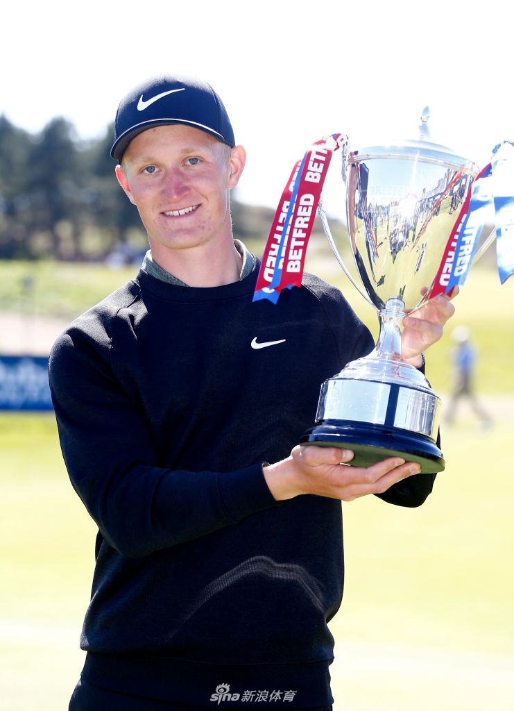 金霍特在果岭上激情庆祝，张开双臂仿佛要拥抱整个球场，身后是碧绿的草场与欢呼的观众。