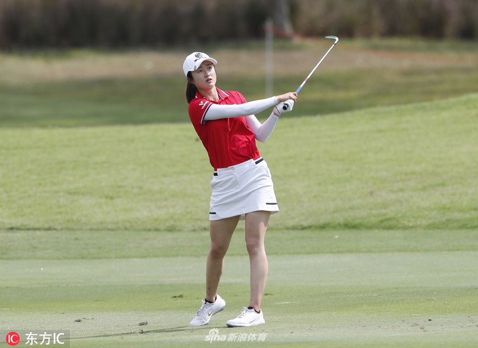 魏圣美在果岭边屈膝审视球位，阳光洒在她专注的脸庞上。