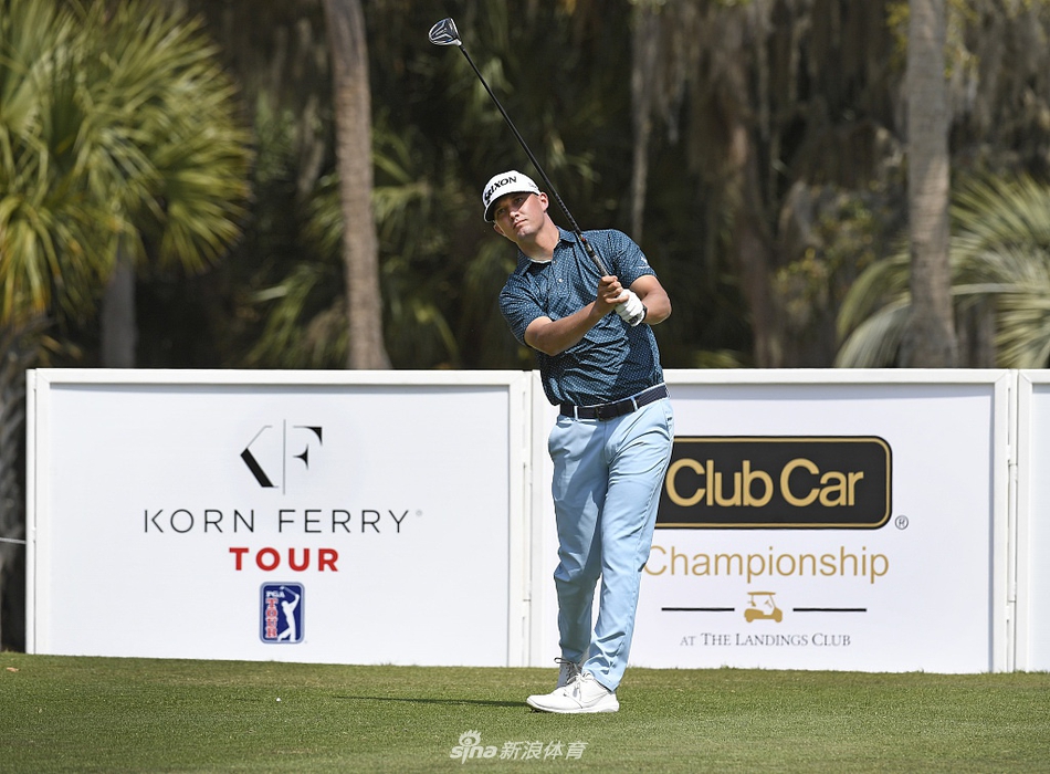 比赛现场全景，广阔的球道与起伏的果岭在阳光下延伸，观众在远处驻足观看，勾勒出职业高尔夫赛事的经典场景。