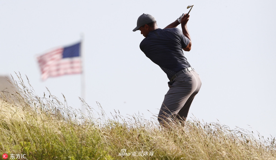 伍兹与同组球员达斯汀·约翰逊一同在球道上行走交流，两位不同时代的王者在这一刻并肩前行。