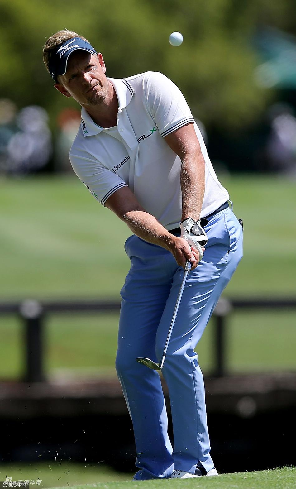 两位知名高尔夫球星在球道上并肩而行，面带微笑轻松交谈，展现了赛场之外的友谊与高尔夫运动的社交魅力。