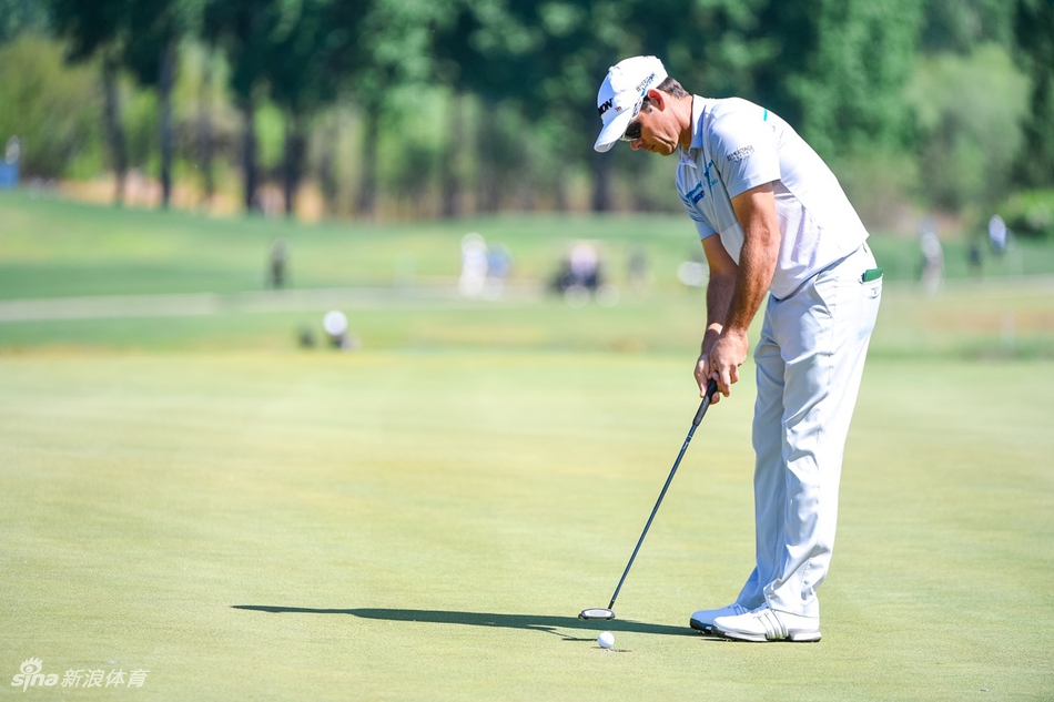 一位高尔夫球手正从沙坑中奋力救球，沙砾飞扬瞬间凝结了力量与技巧，背景是广阔的天空与绿地。