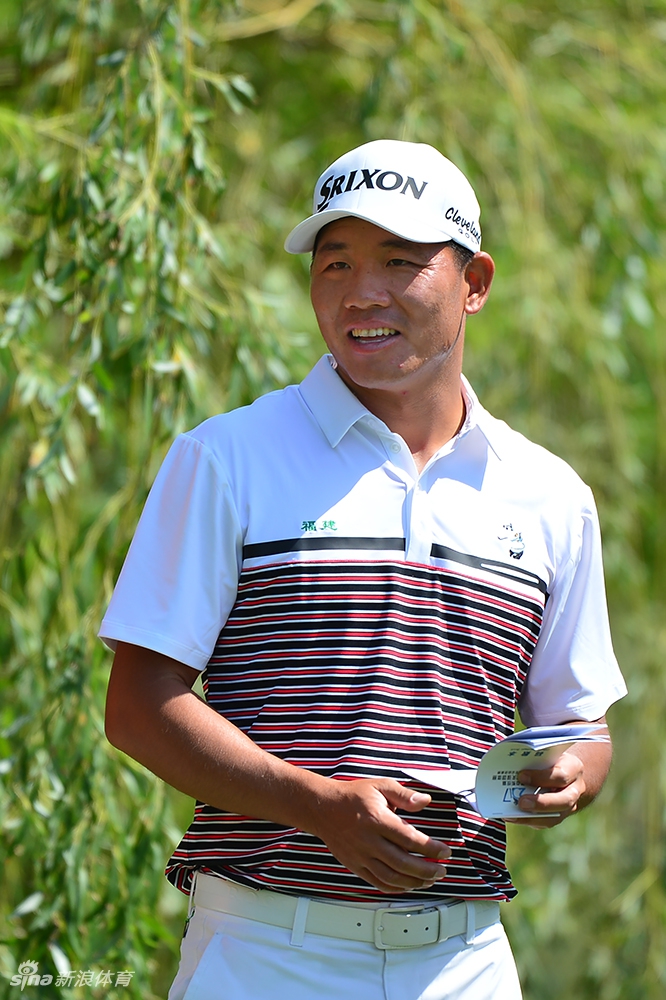 高尔夫比赛现场，球手在沙坑中冷静救球，沙粒飞扬的瞬间充满了挑战性与技巧之美