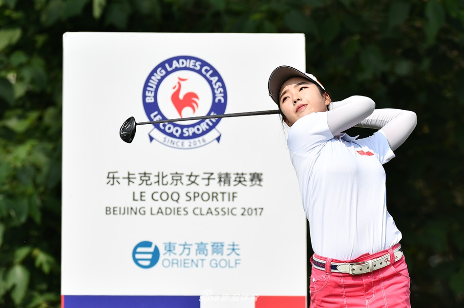 中国球员姜艳姣在果岭边观察推杆线路，她蹲姿专注，正在阅读草坪的细微起伏