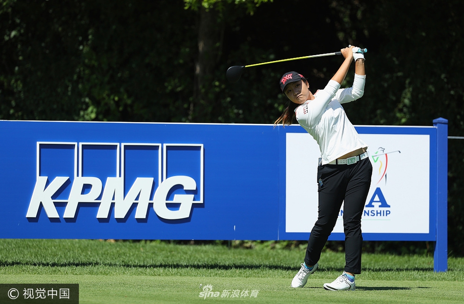 球员们在宽阔的练习果岭上进行推杆练习，背景是奥林匹亚田野乡村俱乐部的经典会所建筑。