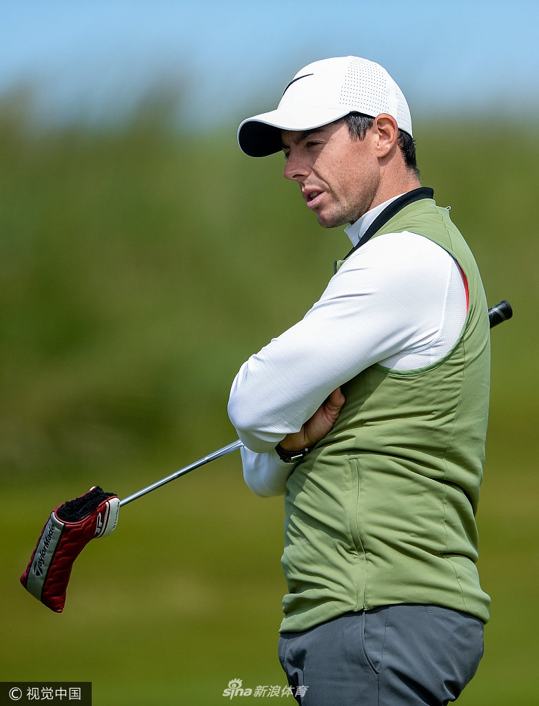 小麦手持推杆,在绿意盎然的练习果岭上进行专注的推击练习。