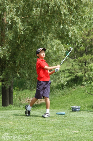 张连伟先生面带微笑将奖杯颁予少年，父亲在一旁欣慰注视，画面温馨感人