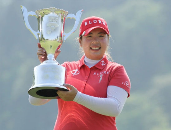 冯珊珊手持冠军奖杯与赛事吉祥物开心合影，脸上洋溢着纯真而自豪的笑容