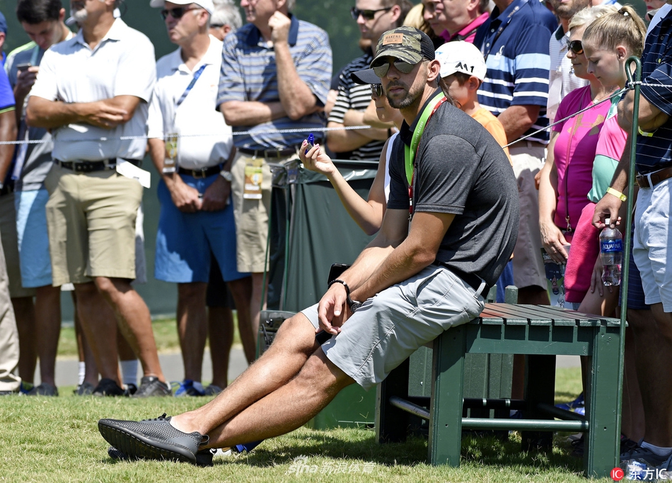 菲尔普斯与加西亚交谈的另一角度，两人均开怀大笑，气氛融洽。菲尔普斯手势生动，似乎在讲述一个有趣的故事，加西亚则拄着球杆倾身聆听，展现了跨项目运动员之间的真诚友谊。