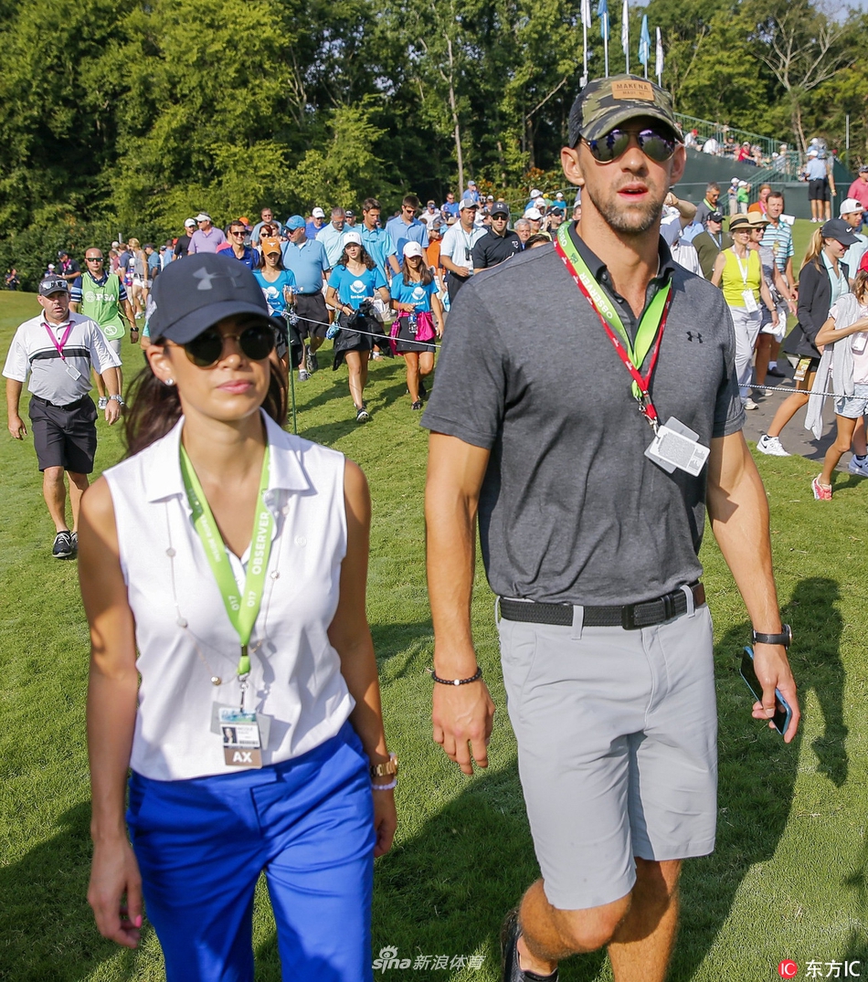 镜头捕捉到菲尔普斯一个专注的侧面特写，他头戴鸭舌帽，目光如炬地望向远方击球的球员，表情认真而投入，展现了他观赛时一如既往的专业态度。