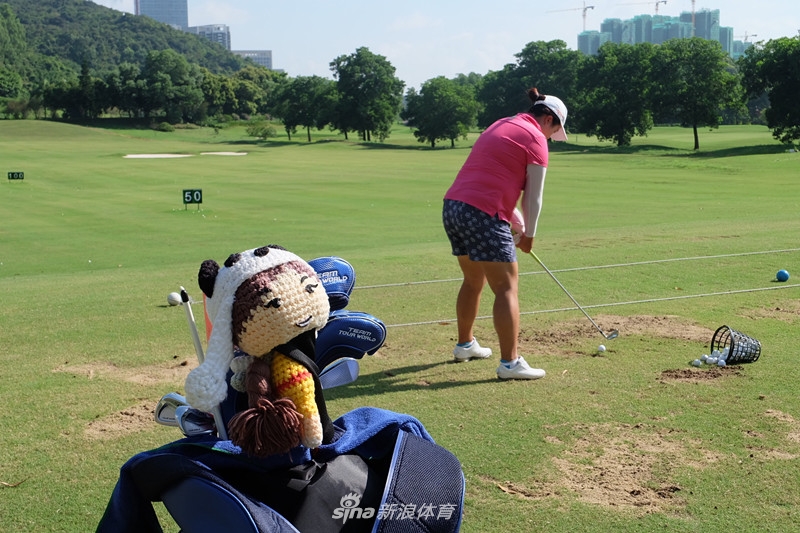 冯珊珊被一群热情的小球迷围在中间，正微笑着在一颗高尔夫球或纪念品上认真签名，满足孩子们的期待。