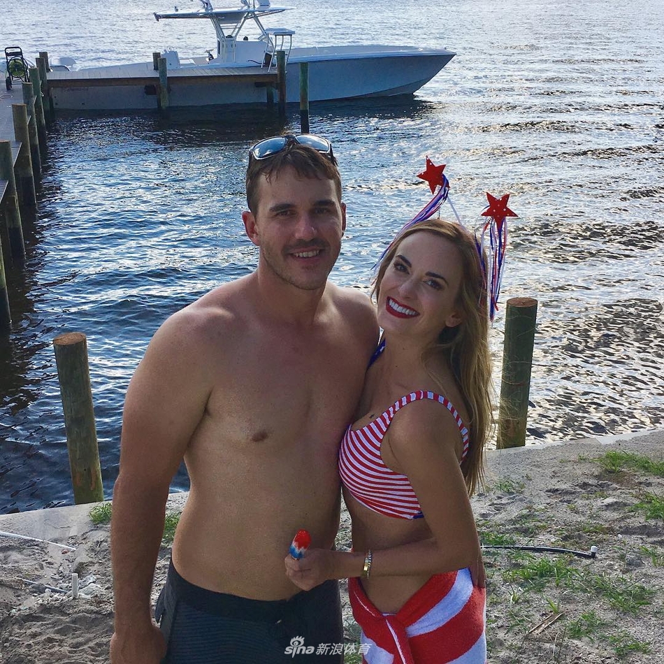 杰娜躺在细腻的沙滩上，身穿鲜艳的印花比基尼，阳光洒落，笑容灿烂，尽显活力与热情。