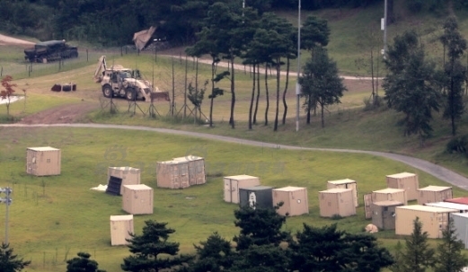 萨德系统的部分组件被迷彩网遮盖，静静停放在开阔的场地上，远处是连绵的山丘，平静之下暗藏着战略态势的巨变。