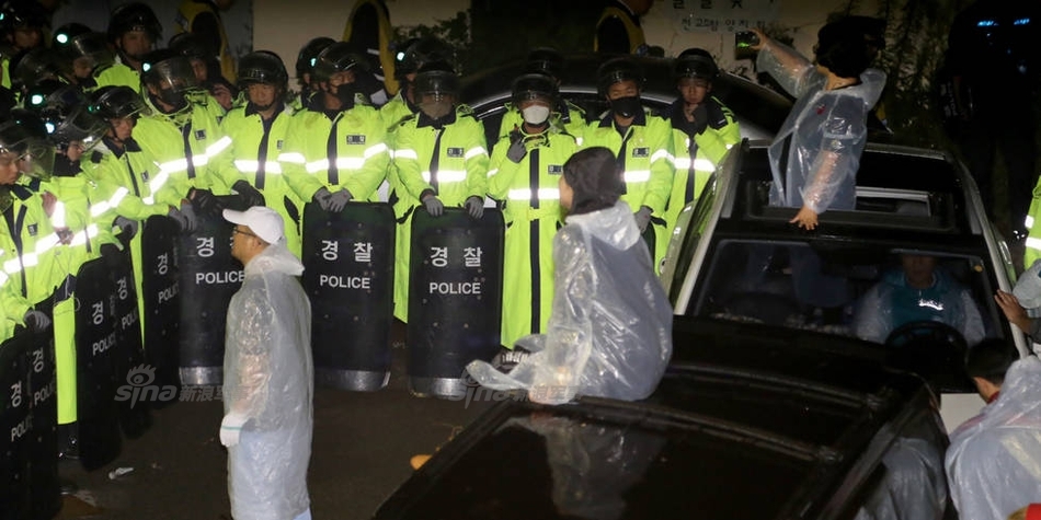 抗议民众情绪激动，紧紧围住军用运输车辆，高举双手呼喊口号，表达他们坚决反对部署的立场。