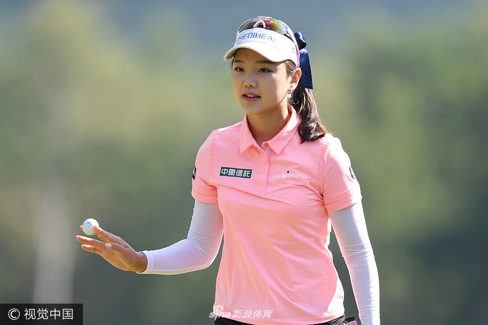 韩国美女球手安信爱在球道上优雅挥杆，身姿与背景的绿茵构成一幅动人画面。