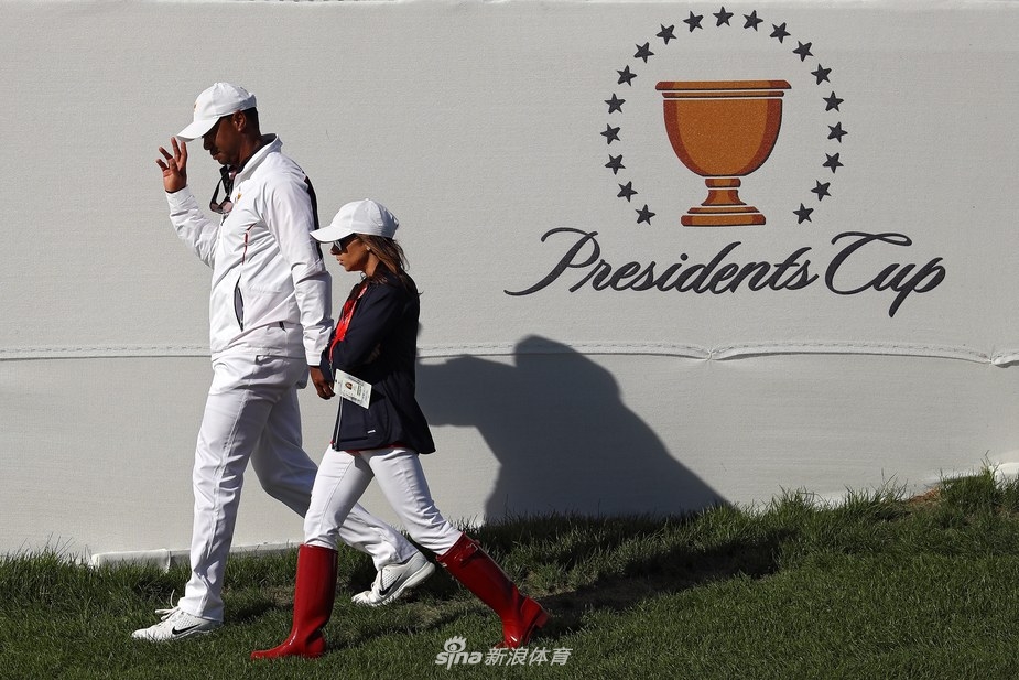 赫尔曼与伍兹站在果岭旁,她微微侧身靠近伍兹,两人似乎正分享着某个轻松的话题