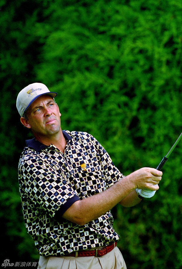 美国队队员在果岭上专注地观察推杆线路,阳光洒在修剪平整的草地上,勾勒出运动员凝神思考的剪影