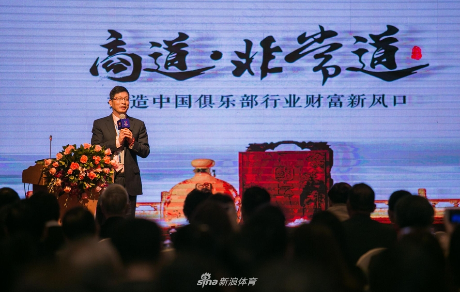 一位与会者正在认真翻阅会议资料手册，表情专注，周围是其他正在交流或步入会场的参会代表。