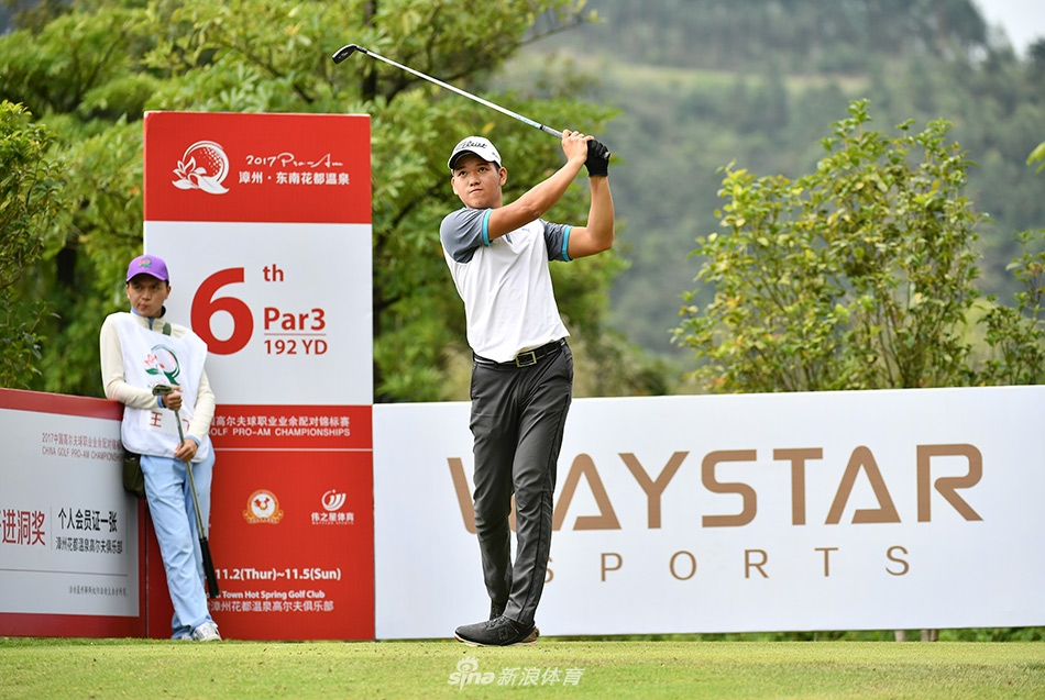 老将吴伟煌与身旁的球童正在认真商讨攻果岭的策略，神情专注。