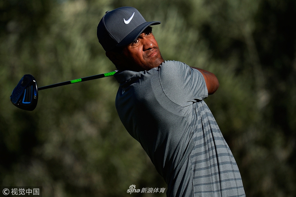 一位球员在茂密的高草区中弯腰艰难地寻找击偏的 golf ball，展现了比赛在狂风下的不可预测性与挑战性。