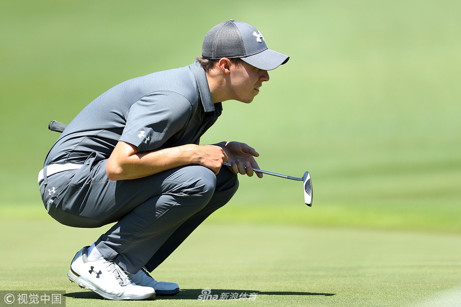 马修·菲茨帕特里克蹲在果岭边，用手指细致地丈量推杆线路，表情专注而严肃。