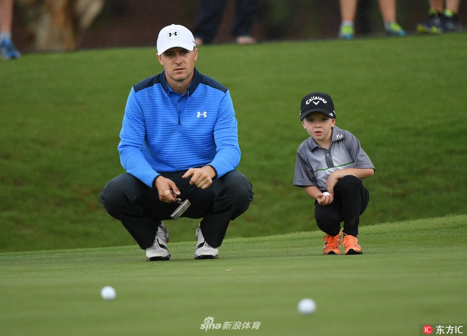 乔丹·斯皮思弯腰俯身,与一位年轻的小球手一同专注地观察果岭推杆线路,眼神中充满了鼓励与分享。