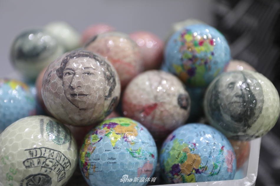 展台一角陈列着系列青花瓷风格的高尔夫球,白底蓝花,图案有山水、花鸟,静置于丝绒盒中宛如艺术品。