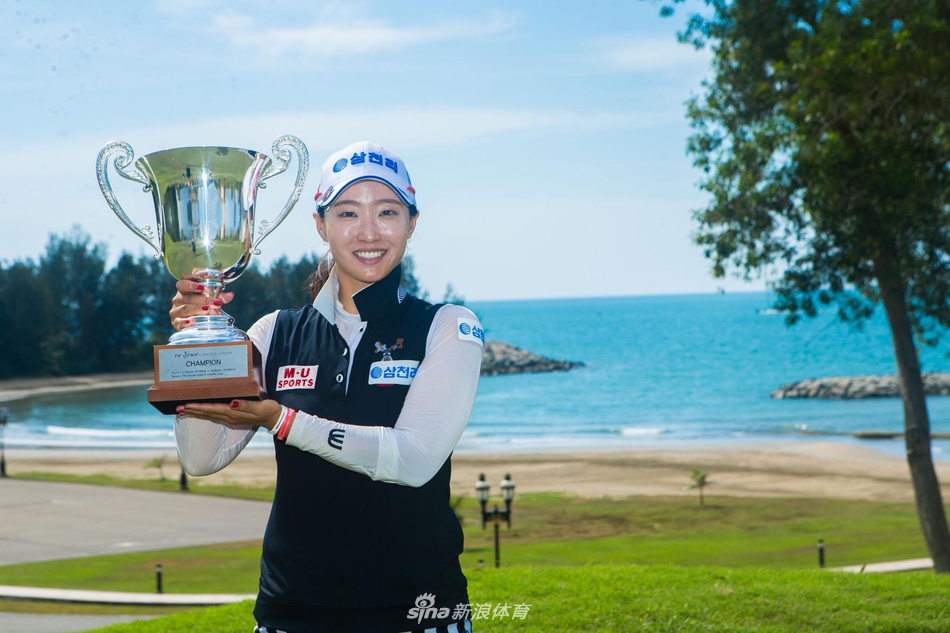 洪兰屈膝蹲在果岭边，指尖轻触草面，正聚精会神地审视推杆进洞的微妙线路