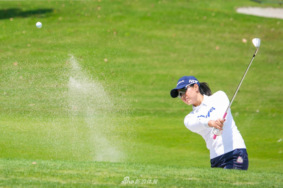 林冶舟站在水障碍旁的球道上，从容不迫地观察落点，身后静谧的湖水映衬着她沉着冷静的身影。