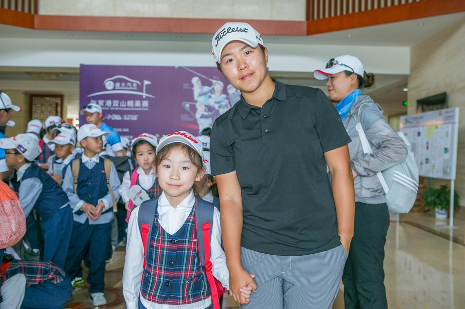 阳光下一名红衣少年自信挥杆，动作流畅有力，展现高尔夫未来之星的风采