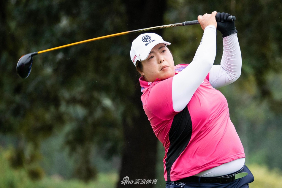 菲律宾球员热努卡优雅挥杆，动作一气呵成，背景的绿茵与雨雾衬托出她流畅的身姿。