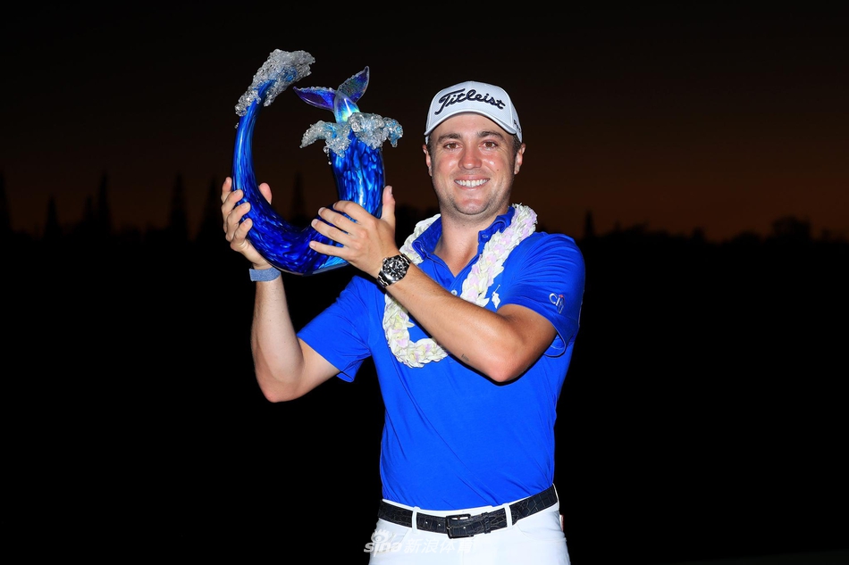 贾斯汀·托马斯在卡帕鲁瓦的果岭上凝神观察推杆线路，远处是夏威夷壮丽的太平洋海景。