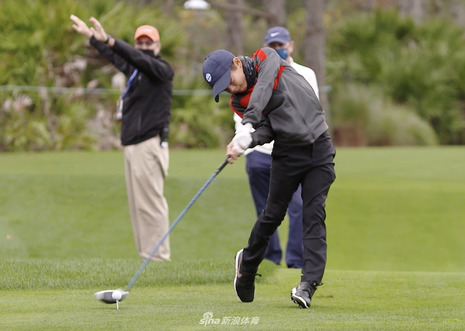 老虎伍兹在沙坑中示范救球，扬起一片沙尘，向儿子亲身传授实战技巧。