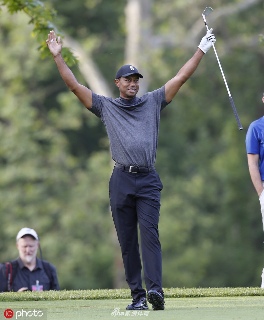 伍兹在开球区凝神准备，阳光勾勒出他专注的侧影，手中球杆即将划破空气，开启又一记精准的击球。