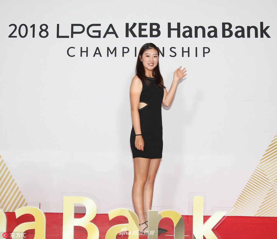 练习果岭上，一名球员正俯身专注地观察推杆线路，她的眼神沉着，身旁的球包与远处朦胧的球场建筑共同构成了一幅宁静而专业的赛前备战图景。