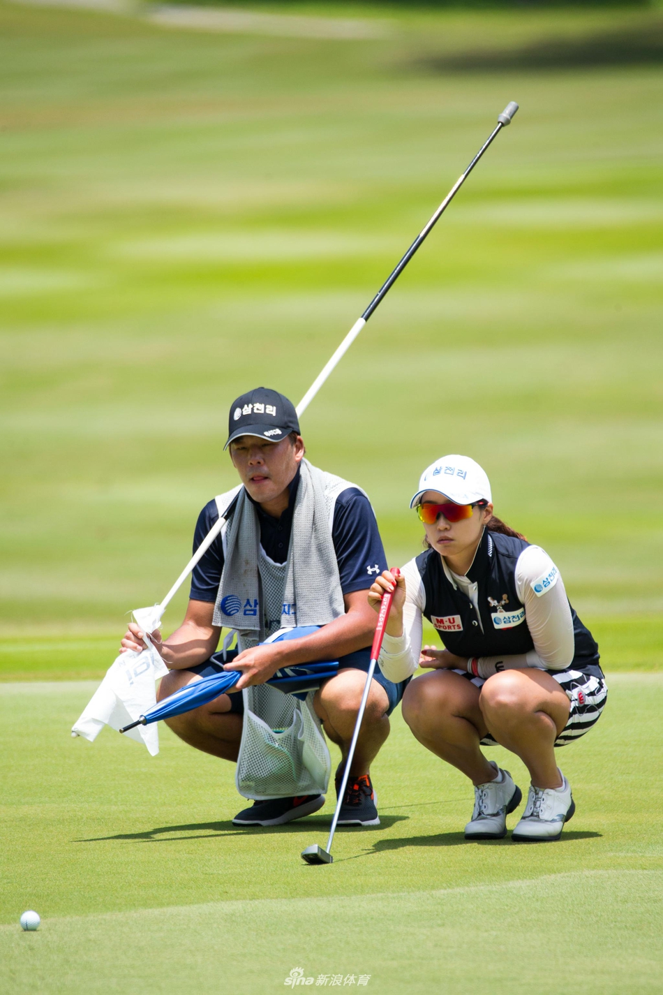 洪兰与身旁伙伴高举右手激情击掌，笑容洋溢，背后是广阔的比赛球场与蓝天