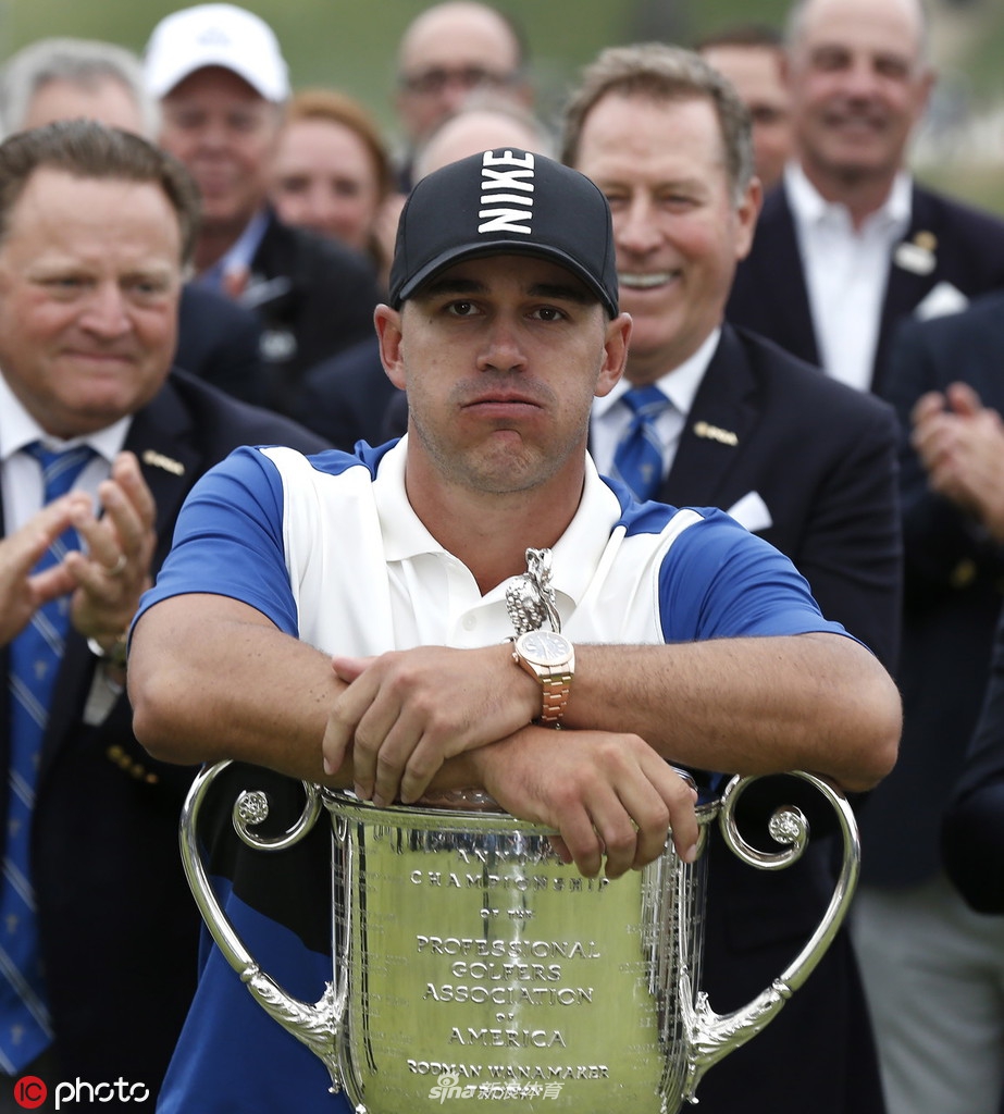 科普卡与决赛轮同组球员及球童在记分处确认成绩，背景中赛事记分板清晰记录着跌宕起伏的战况。