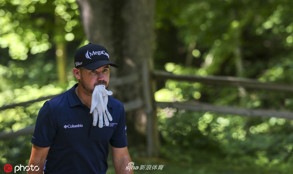 一位球员在TPC鹿场经典的岛型果岭旁进行切杆，水障碍环绕，击球需要极高的精准度与勇气。