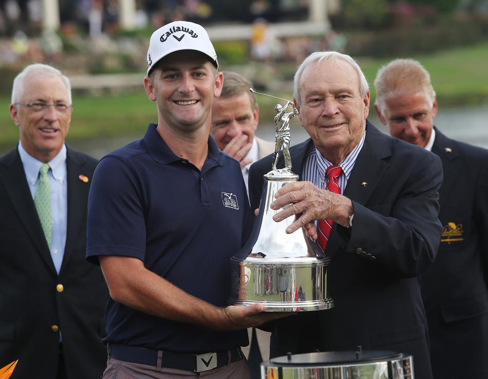 冠军弗朗西斯科·莫里纳利高高举起阿诺德·帕尔默邀请赛奖杯，红色开衫在聚光灯下格外耀眼。