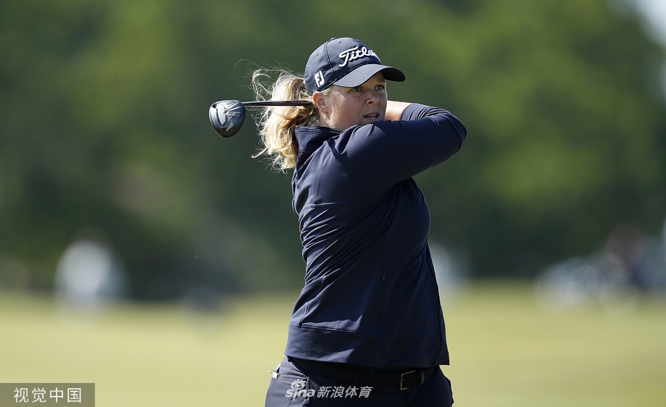 女球手在果岭边沉着进行切杆评估，神情专注而自信