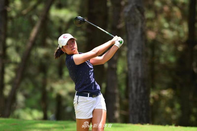 小球员在黄山松柏球场果岭边专注推杆，眼神沉着，徽派建筑静静伫立在远方天际线下。