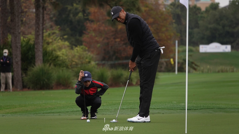 老虎伍兹全神贯注地注视着儿子查理的挥杆动作，眼神中满是父亲的专注与骄傲。