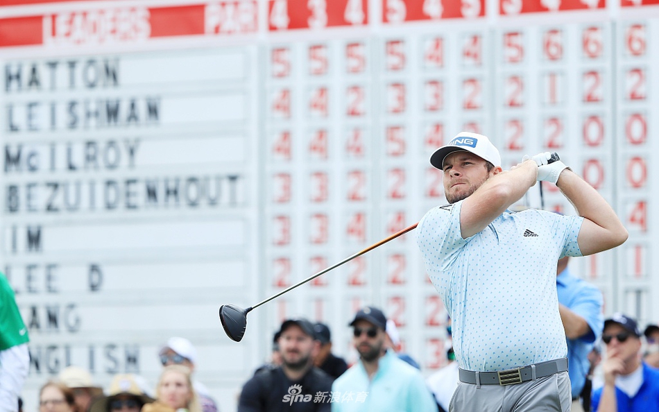 帕尔默的外孙山姆·桑德斯面带微笑，正将象征赛事荣耀的红色开衫披在新冠军哈顿肩上。